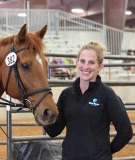 Laura de pie junto a un caballo numerado después de competir.